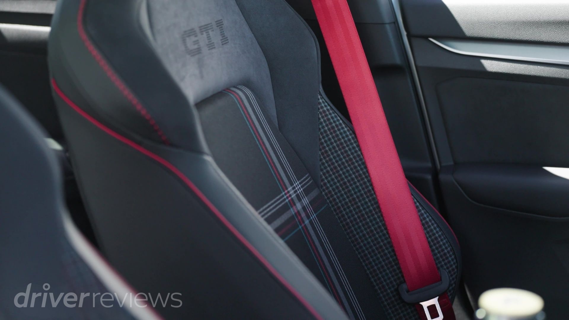 Close-up of the Golf GTI Edition 50's tartan seat trim, GTI embroidery, and red seatbelt